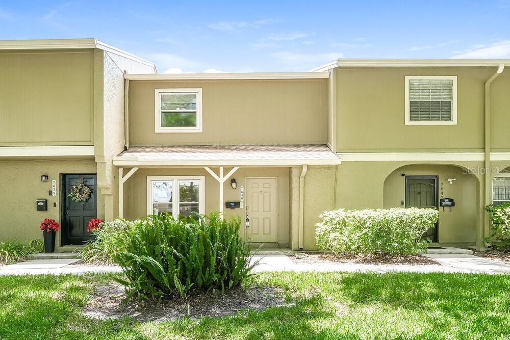 A row of three attached townhomes with tan stucco siding and dark front doors — 7640 WOODBRIDGE BOULEVARD, TAMPA, FL