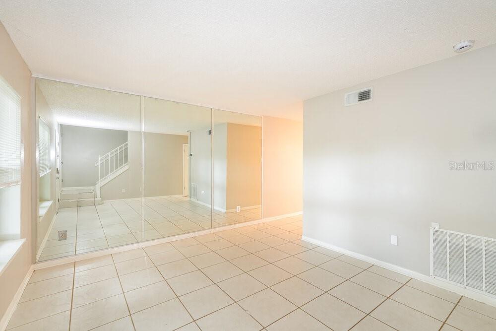 A room with light-colored tile flooring, a large mirrored wall, and a white staircase — 7640 WOODBRIDGE BOULEVARD, TAMPA, FL