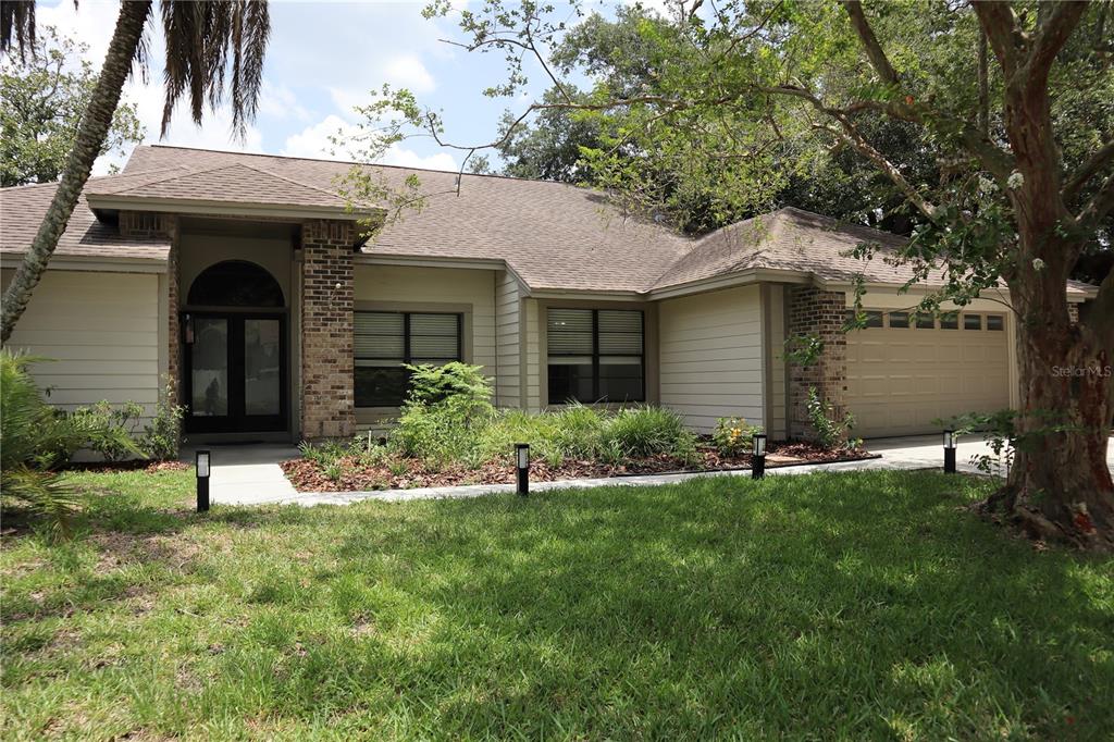 A single-story house with tan siding, brick accents, and a two-car garage — 10428 TARA DRIVE, RIVERVIEW, FL