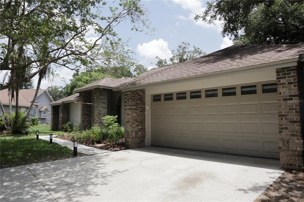 A single-story house with a beige garage door, brick accents, and a concrete driveway — 10428 TARA DRIVE, RIVERVIEW, FL