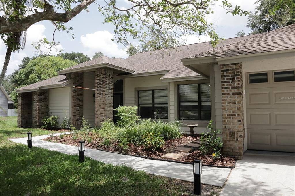 A single-story house with a brick-accented facade, a garage, and a landscaped front walkway — 10428 TARA DRIVE, RIVERVIEW, FL