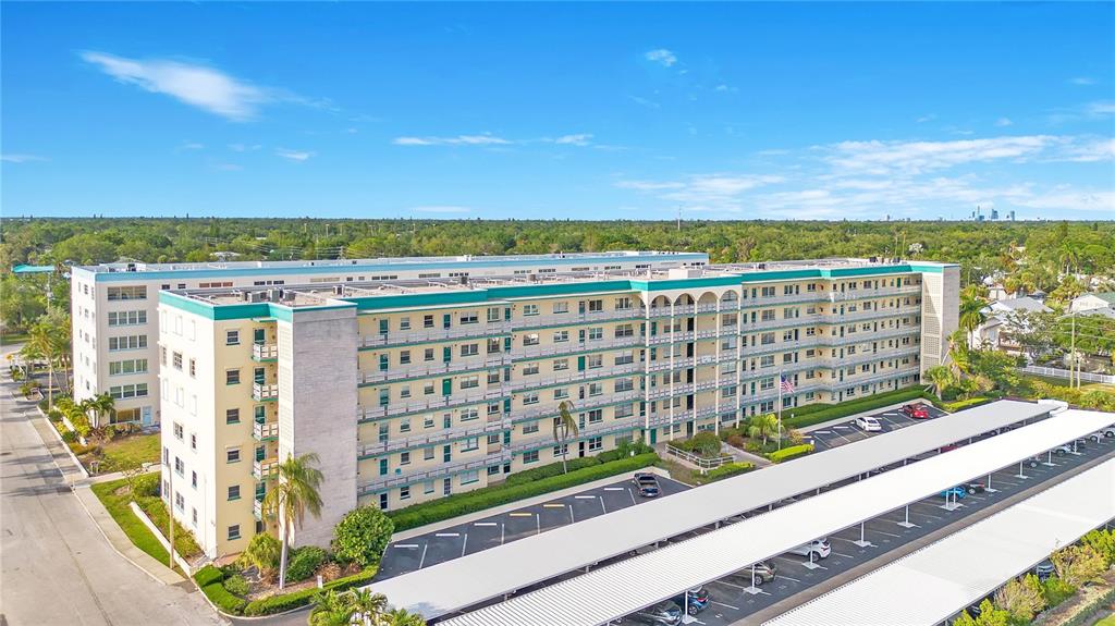 An aerial view shows a multi-story apartment building with a large parking lot and carports — 2960 59TH STREET S UNIT 405, GULFPORT, FL