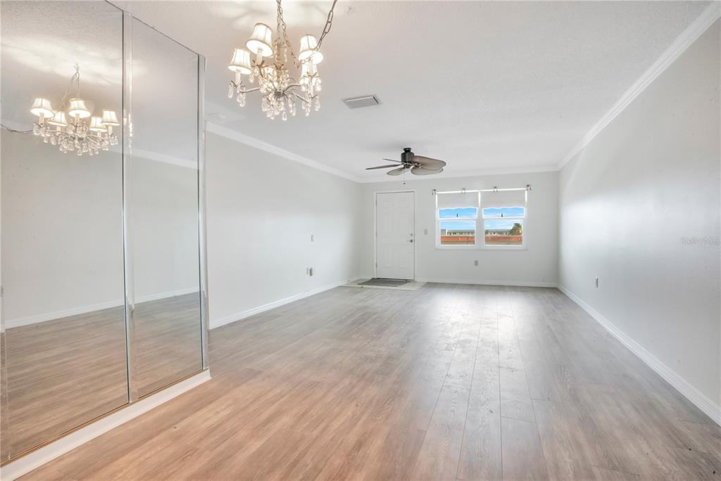 A bright room with wood-look flooring, a mirrored closet, a chandelier, and a ceiling fan — 2960 59TH STREET S UNIT 405, GULFPORT, FL