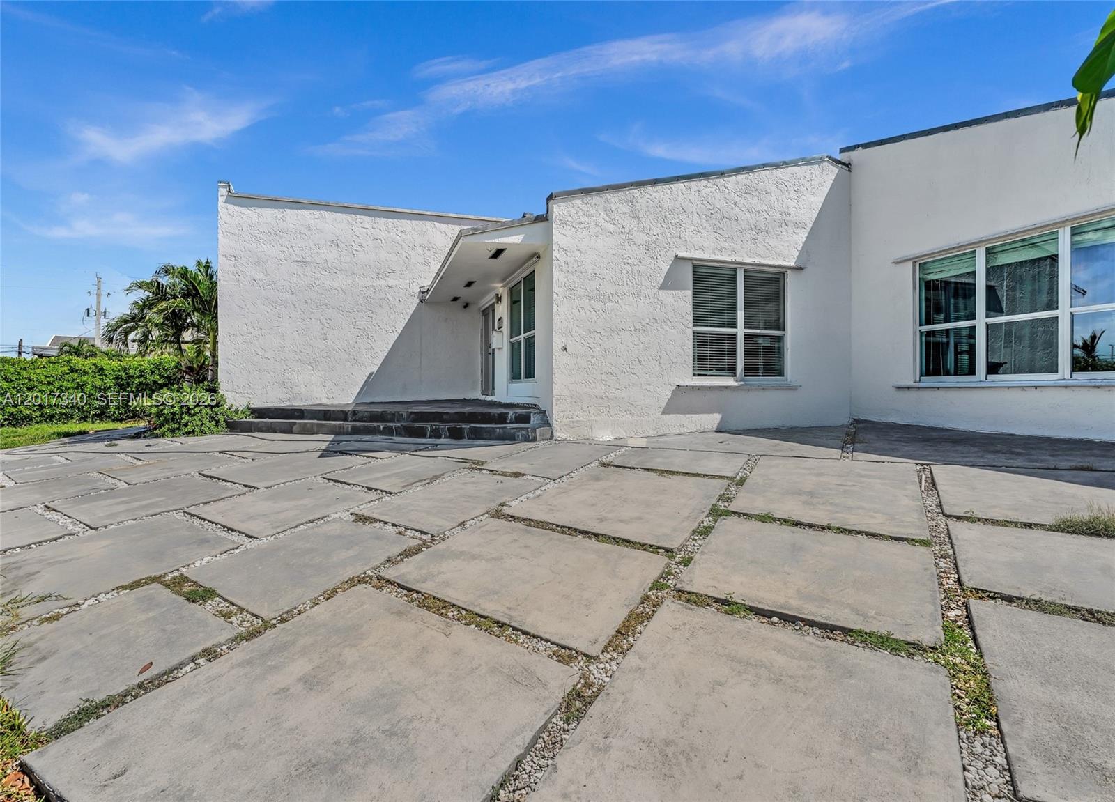 A white stucco house features a concrete paver driveway and a recessed front entrance — 2001 NE 122nd Rd, North Miami FL 33181, NORTH MIAMI, FL