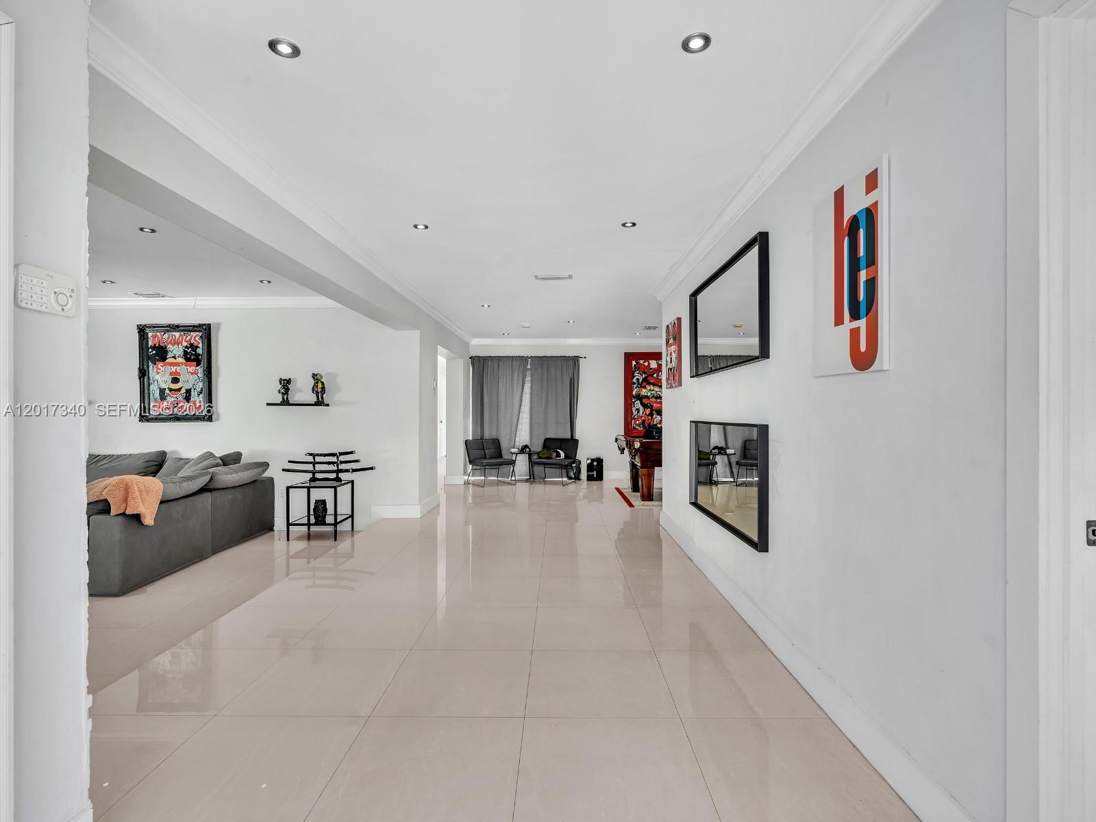 A spacious, brightly lit living area features white tile floors, recessed lighting, and modern decor — 2001 NE 122nd Rd, North Miami FL 33181, NORTH MIAMI, FL