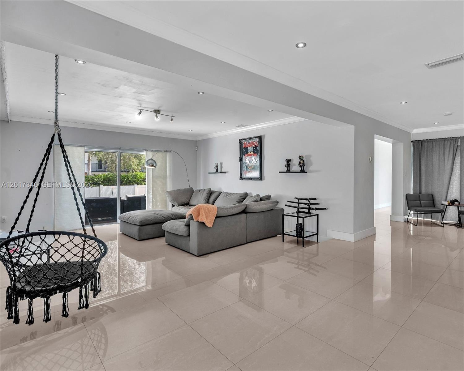 A living room features a hanging chair, a gray sectional sofa, and light tile flooring — 2001 NE 122nd Rd, North Miami FL 33181, NORTH MIAMI, FL