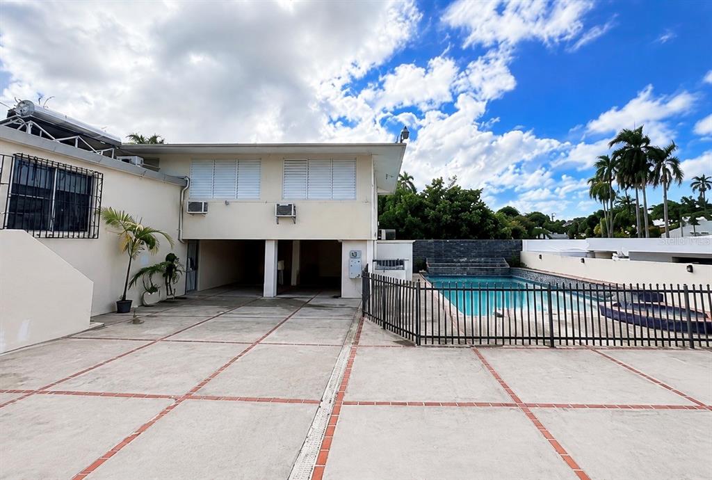 A two-story house exterior features a concrete driveway, a swimming pool, and palm trees — D-15 GREEN VALLEY UNIT D-15, GUAYNABO, PR