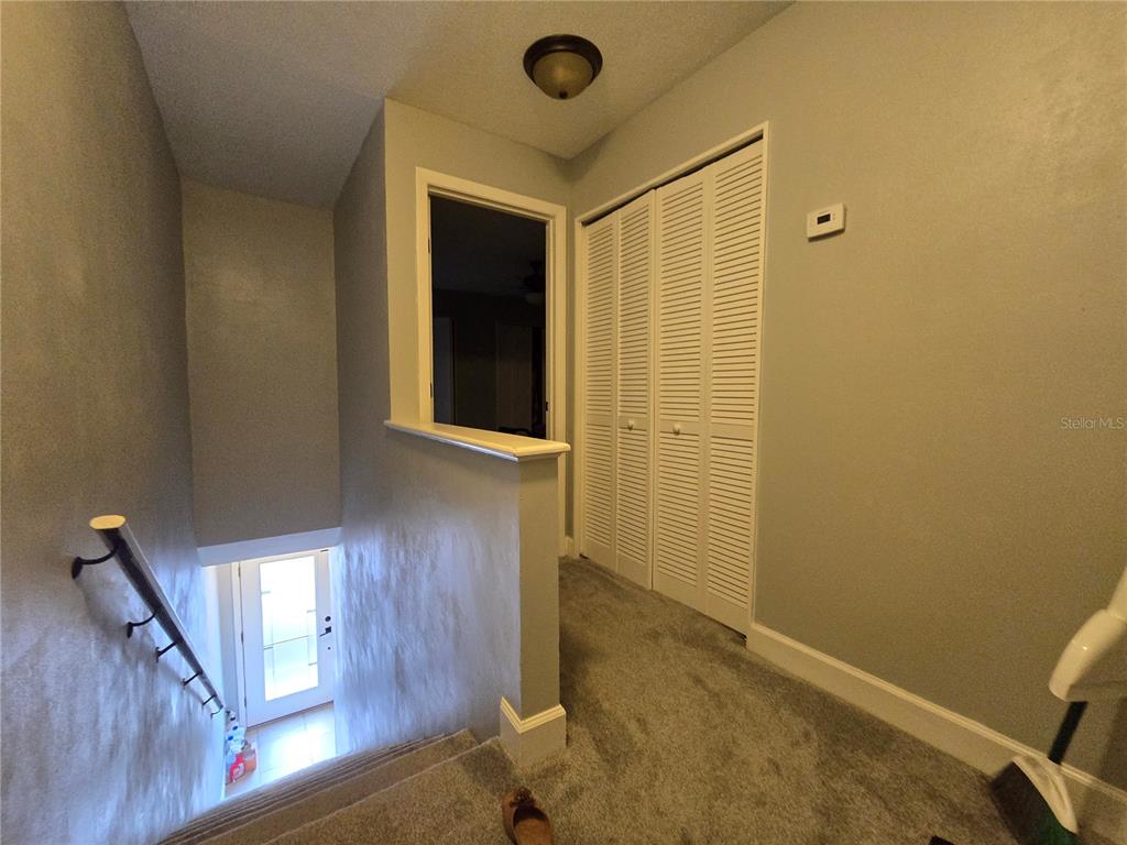 A carpeted landing features a staircase, a closet with louvered doors, and a wall cutout — 2115 NE 38TH AVENUE, OCALA, FL