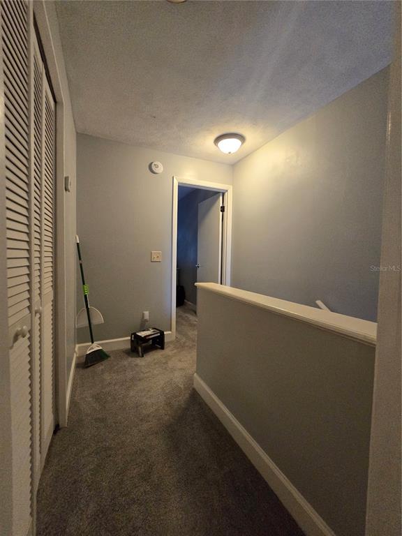 A carpeted hallway features a louvered closet door, a light fixture, and a stair railing — 2115 NE 38TH AVENUE, OCALA, FL
