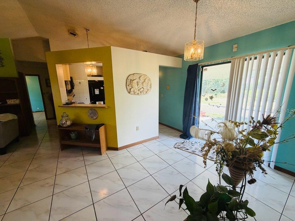 A living area with white tile floors, a yellow accent wall, and sliding glass doors — 450 TOPEKA, PALM BAY, FL