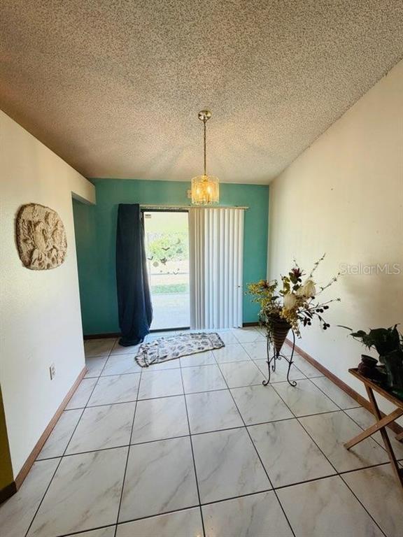 A dining area features white marble-look tile flooring, a teal accent wall, and a sliding door — 450 TOPEKA, PALM BAY, FL
