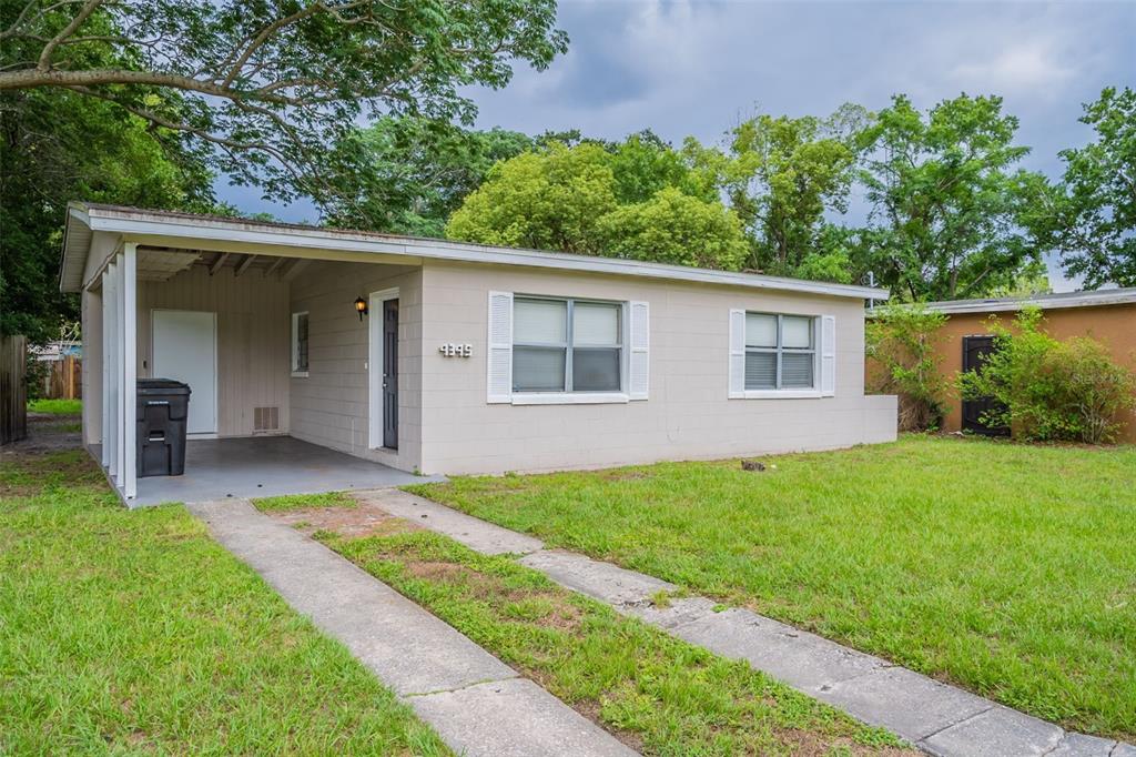 A single-story beige house with a carport and a concrete driveway sits on a lawn — 4345 AETNA DRIVE, ORLANDO, FL