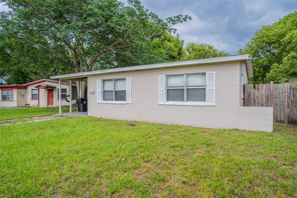 A single-story beige concrete block house with a covered porch and a grassy front yard — 4345 AETNA DRIVE, ORLANDO, FL