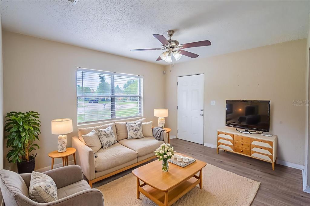 A living room features a beige sofa, wooden coffee table, television console, and ceiling fan — 4345 AETNA DRIVE, ORLANDO, FL