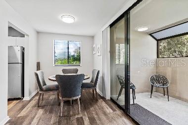 A dining area with wood-look flooring sits adjacent to a glass-enclosed balcony with two chairs — 3071 WILLOW GREEN UNIT 35, SARASOTA, FL