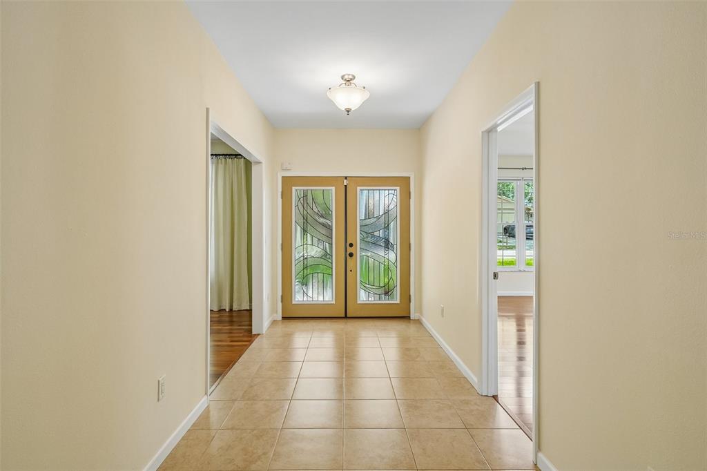 A tiled entryway features double front doors with decorative glass panels and two side doorways — 818 VILLAGE WAY, PALM HARBOR, FL