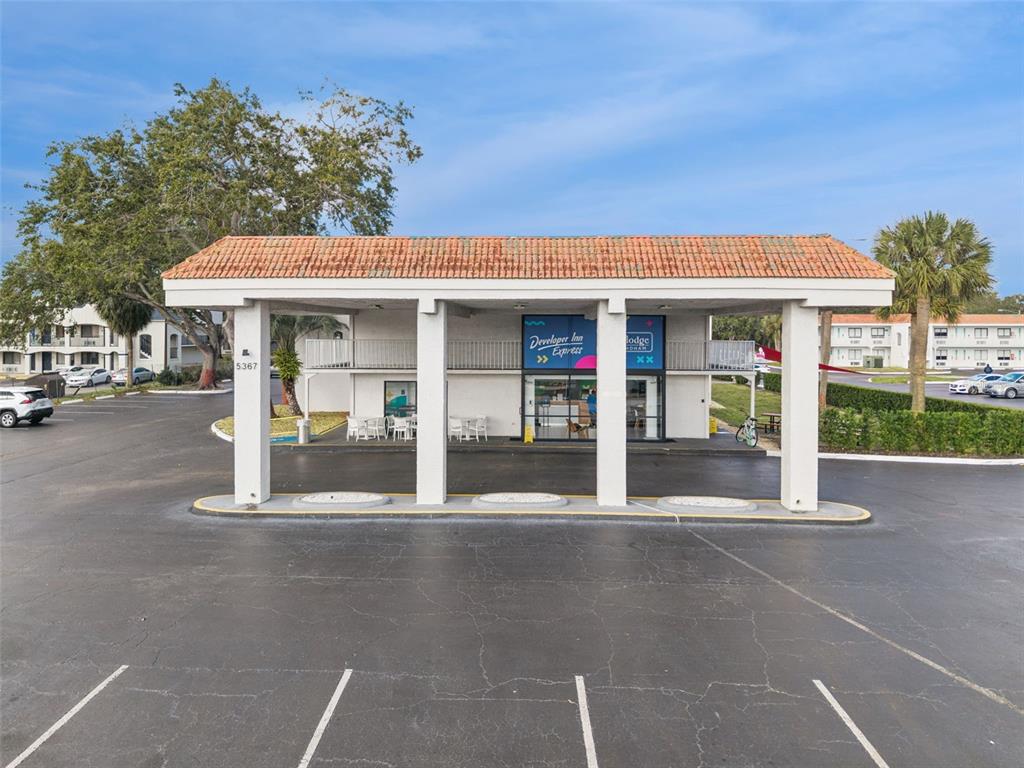 A low-rise hotel building features a covered porte-cochère entrance with white columns and tiled roofing — 5367 W IRLO BRONSON MEMORIAL HIGHWAY UNIT 1-209, KISSIMMEE, FL