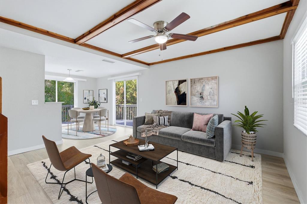 A living room with wood ceiling beams, a gray sofa, and a dining area beyond — 2852 NASSAU STREET, SARASOTA, FL