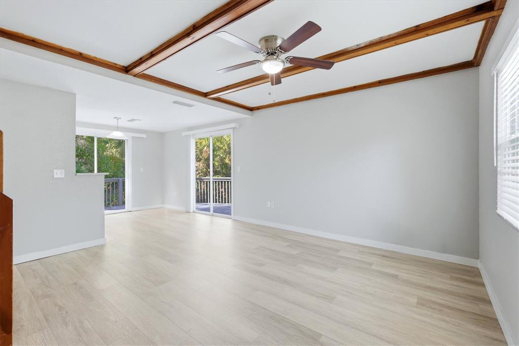 A bright living room features light wood-look flooring, a coffered ceiling with wood beams, and sliding doors — 2852 NASSAU STREET, SARASOTA, FL