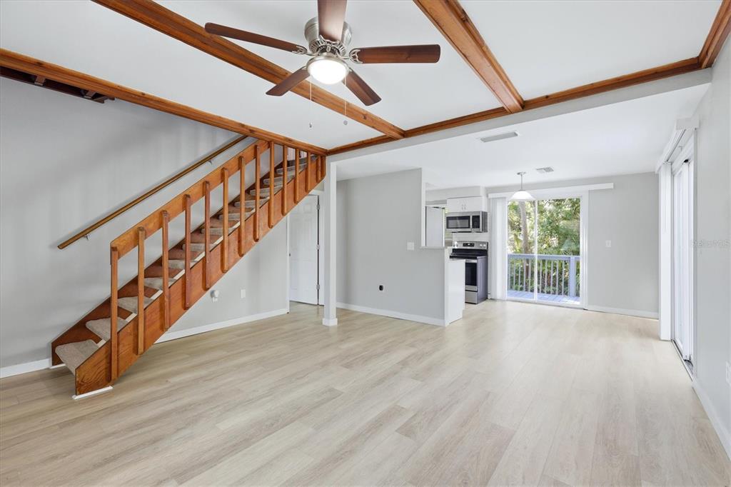 An open-concept living area features light wood flooring, a wooden staircase, and exposed ceiling beams — 2852 NASSAU STREET, SARASOTA, FL