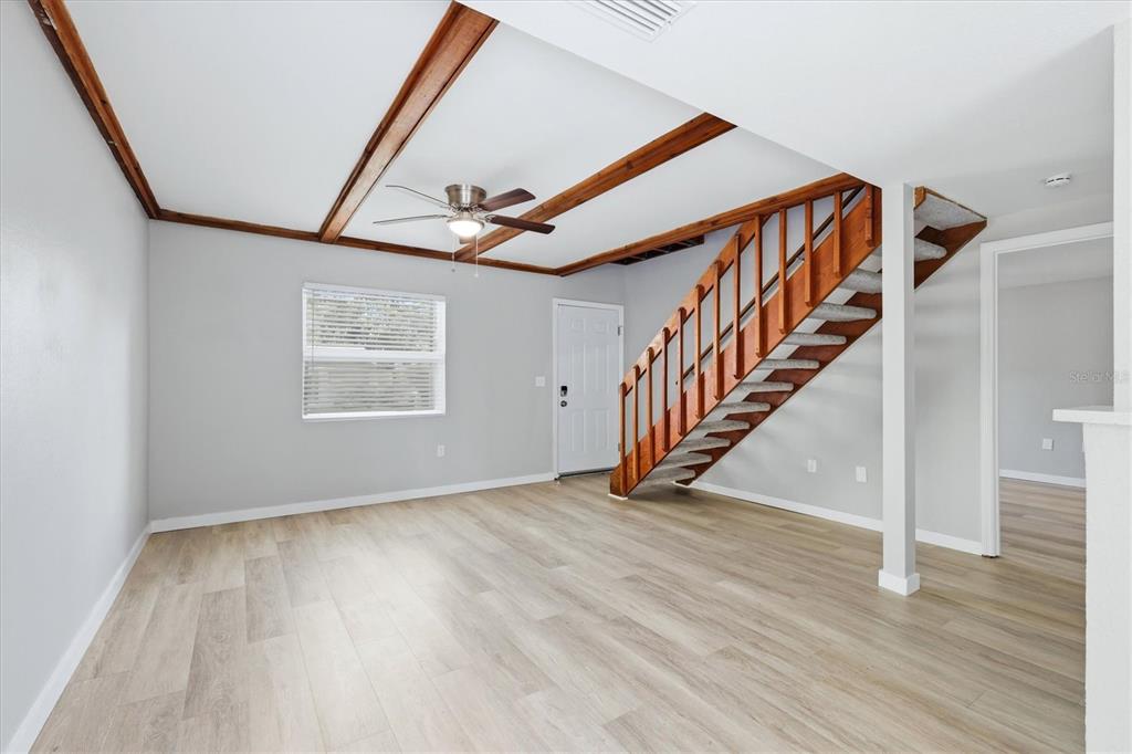 A living room features light wood-look flooring, a vaulted ceiling with exposed beams, and stairs — 2852 NASSAU STREET, SARASOTA, FL