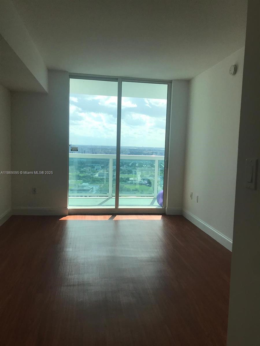 An empty room features wood-look flooring, white walls, and a large sliding glass door — 1800 N Bayshore Dr # 3910, Miami FL 33132, MIAMI, FL