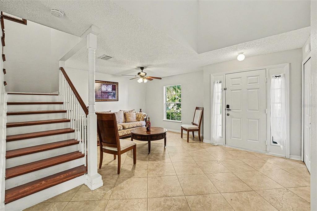 A foyer with tile flooring, a staircase, and a small seating area near the entrance — 2355 ANDREWS VALLEY DRIVE, KISSIMMEE, FL