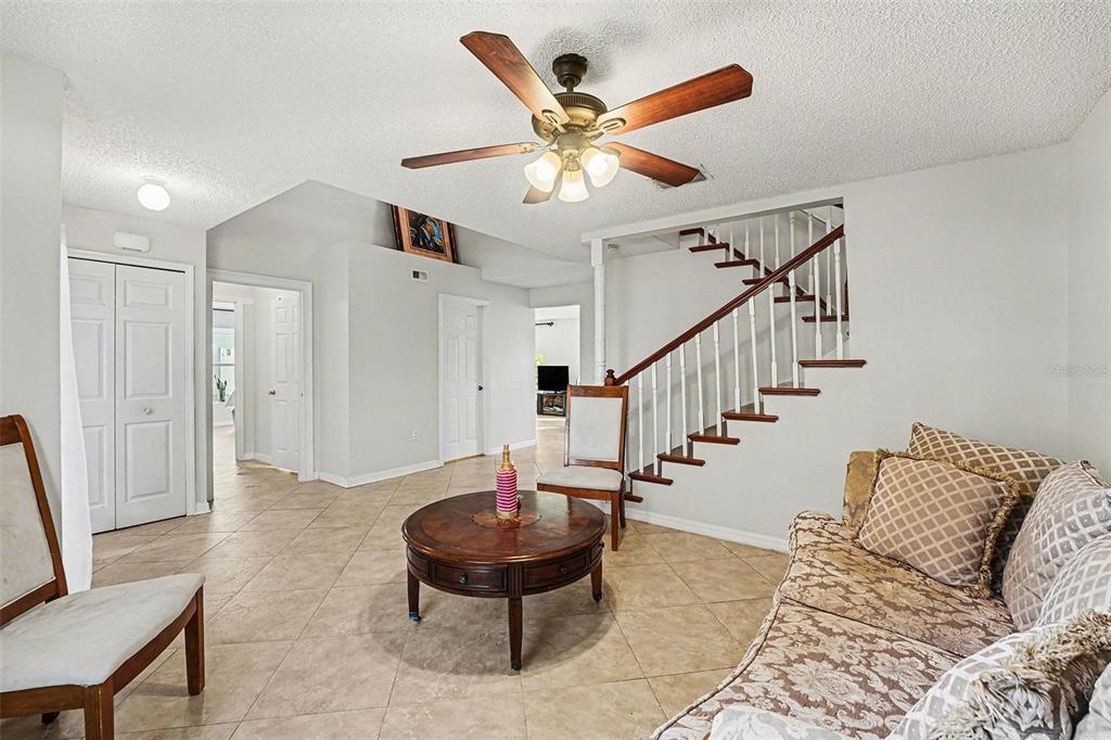 A living room features tile flooring, a wooden staircase, and a ceiling fan — 2355 ANDREWS VALLEY DRIVE, KISSIMMEE, FL