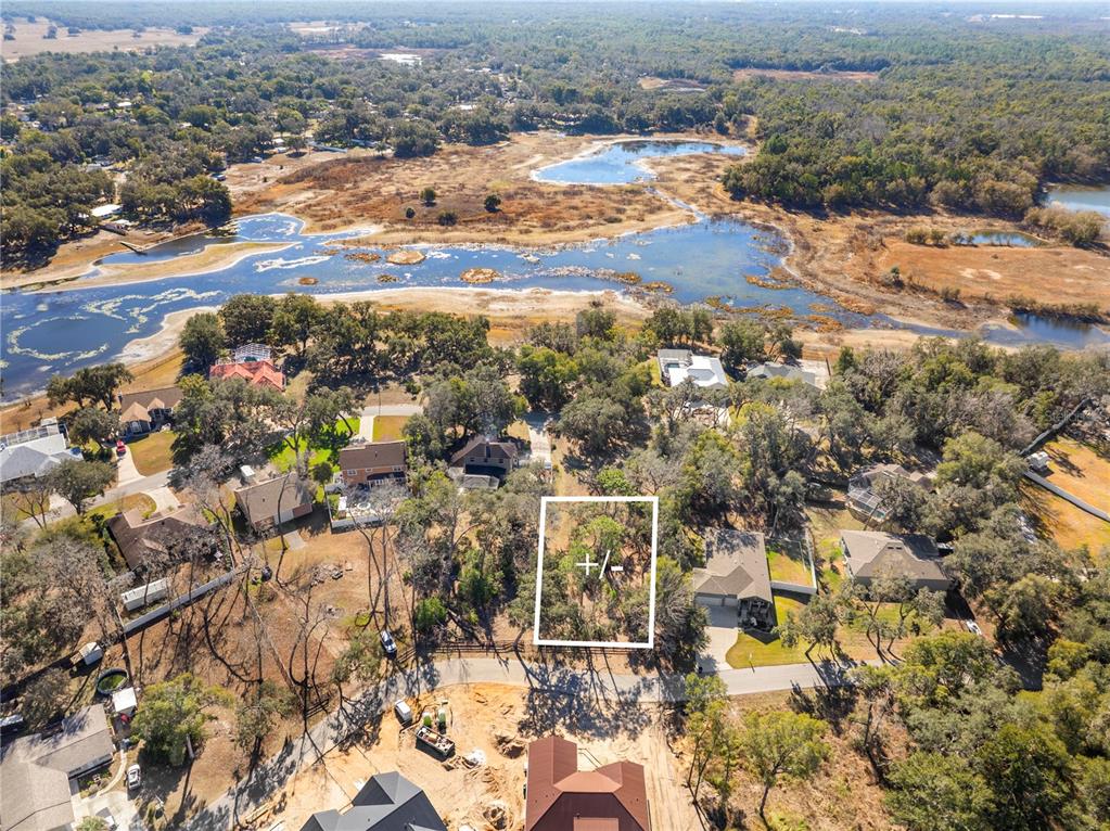 An aerial view shows a vacant, wooded residential lot outlined in white near a lake — 5104 WESTLAKE BOULEVARD, DADE CITY, FL