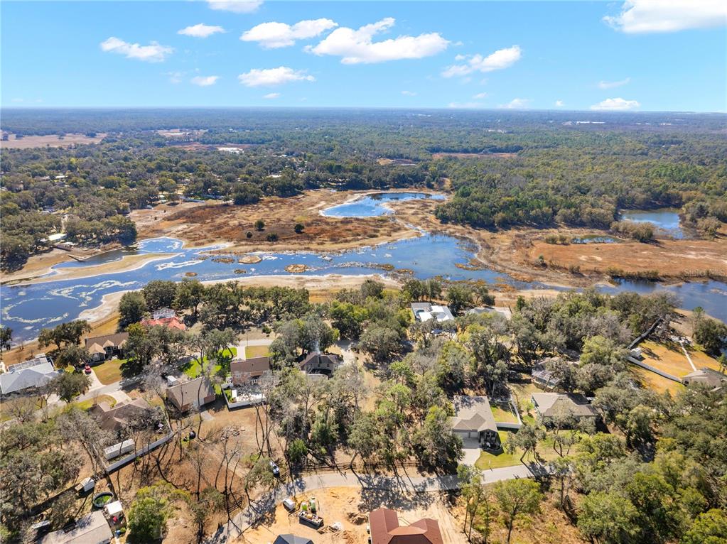An aerial view shows houses nestled among trees next to a large, shallow lake — 5104 WESTLAKE BOULEVARD, DADE CITY, FL