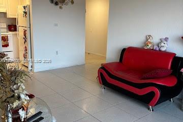 A living room features a red and black sofa, white tile floors, and a refrigerator — 17600 NW 68th Ave # B4002, Hialeah FL 33015, HIALEAH, FL