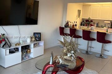 A living room features a white media console, a glass coffee table, and kitchen bar stools — 17600 NW 68th Ave # B4002, Hialeah FL 33015, HIALEAH, FL