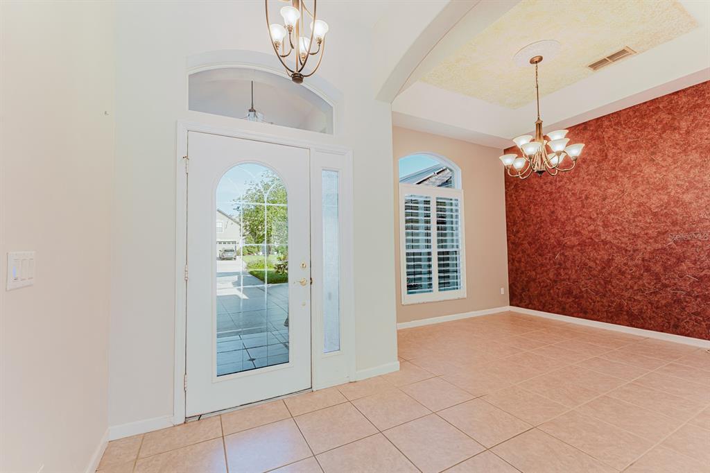 An entryway with tile flooring, a white front door, and a dining room with red walls — 3645 ROCHELLE LANE, APOPKA, FL