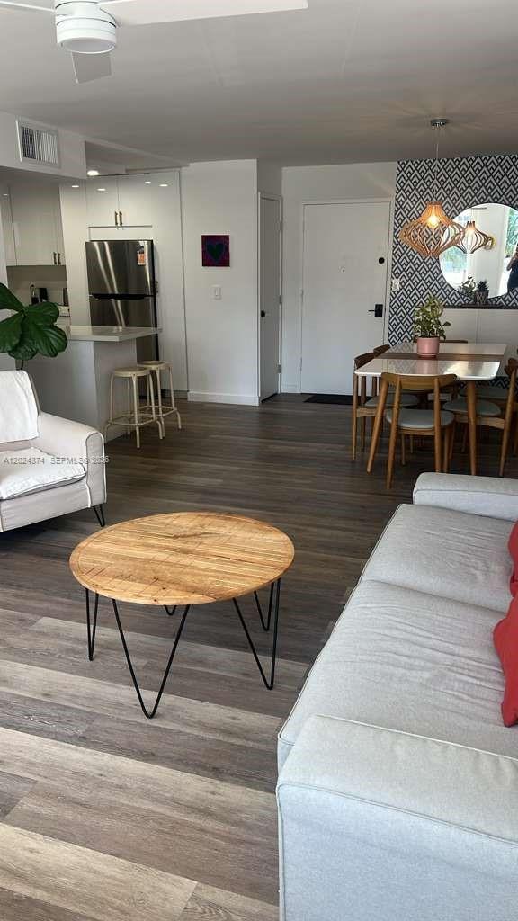 An open-concept living and dining area features wood-look flooring, a kitchen island, and modern furniture — 1913 S.Ocean dr. # 429, Hallandale Beach FL 33009, HALLANDALE BEACH, FL