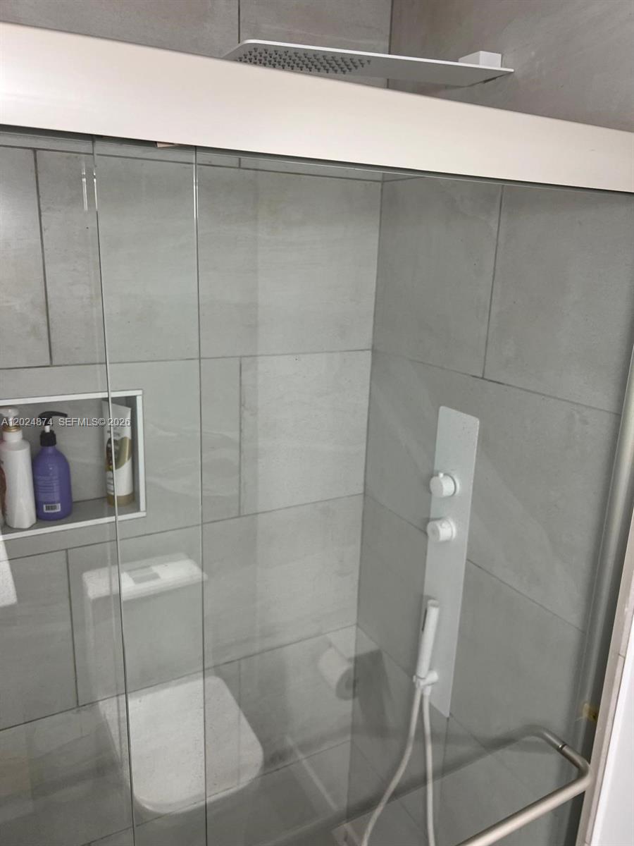 A glass-enclosed shower features gray tiled walls, a rainfall showerhead, and a built-in niche — 1913 S.Ocean dr. # 429, Hallandale Beach FL 33009, HALLANDALE BEACH, FL