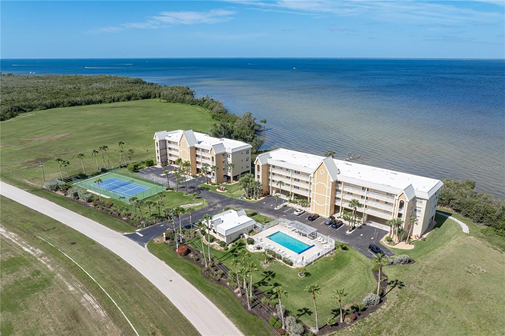 An aerial view shows two multi-story apartment buildings with a pool and tennis court nearby — 101 N MARION COURT UNIT 215, PUNTA GORDA, FL