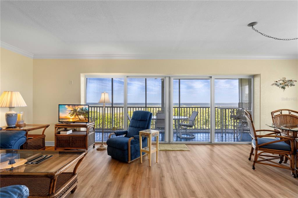 A living room features wood-look flooring, a blue recliner, and sliding glass doors overlooking water — 101 N MARION COURT UNIT 215, PUNTA GORDA, FL