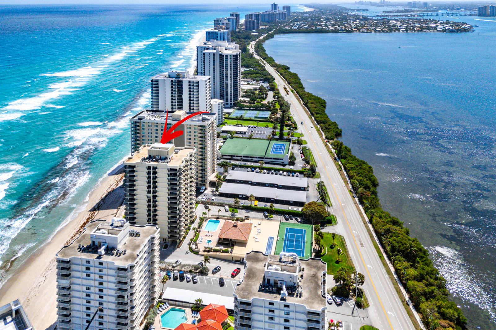 An aerial view shows high-rise residential buildings along a beach with tennis courts and pools — 5460 N Ocean Drive # 5b, Singer Island FL 33404, SINGER ISLAND, FL