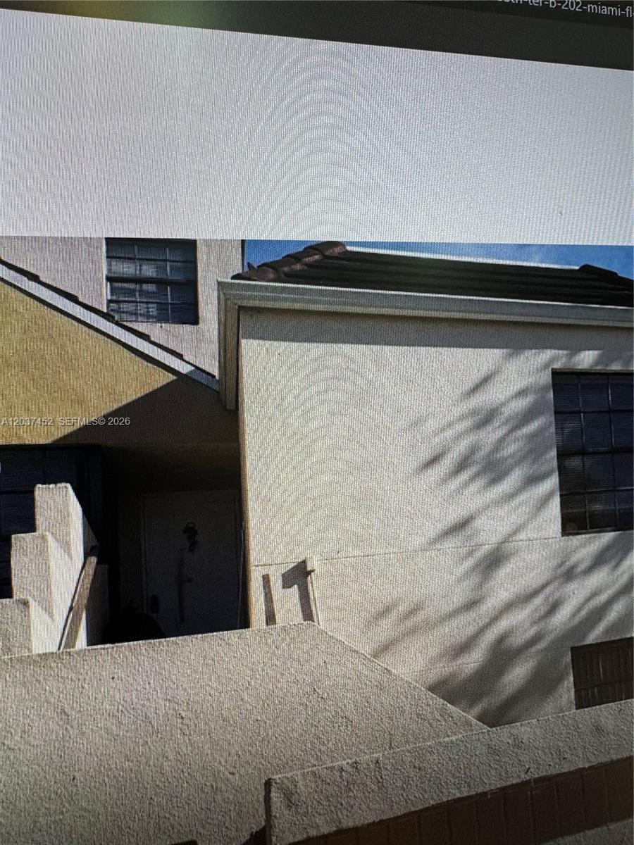 The exterior of a multi-story stucco building features a recessed entryway and a number 11 — 12910 SW 88th Ter # 203, Miami FL 33186, MIAMI, FL