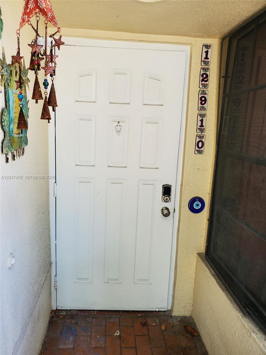 A white front door with a smart lock and decorative address tiles on the wall — 12910 SW 88th Ter # 203, Miami FL 33186, MIAMI, FL