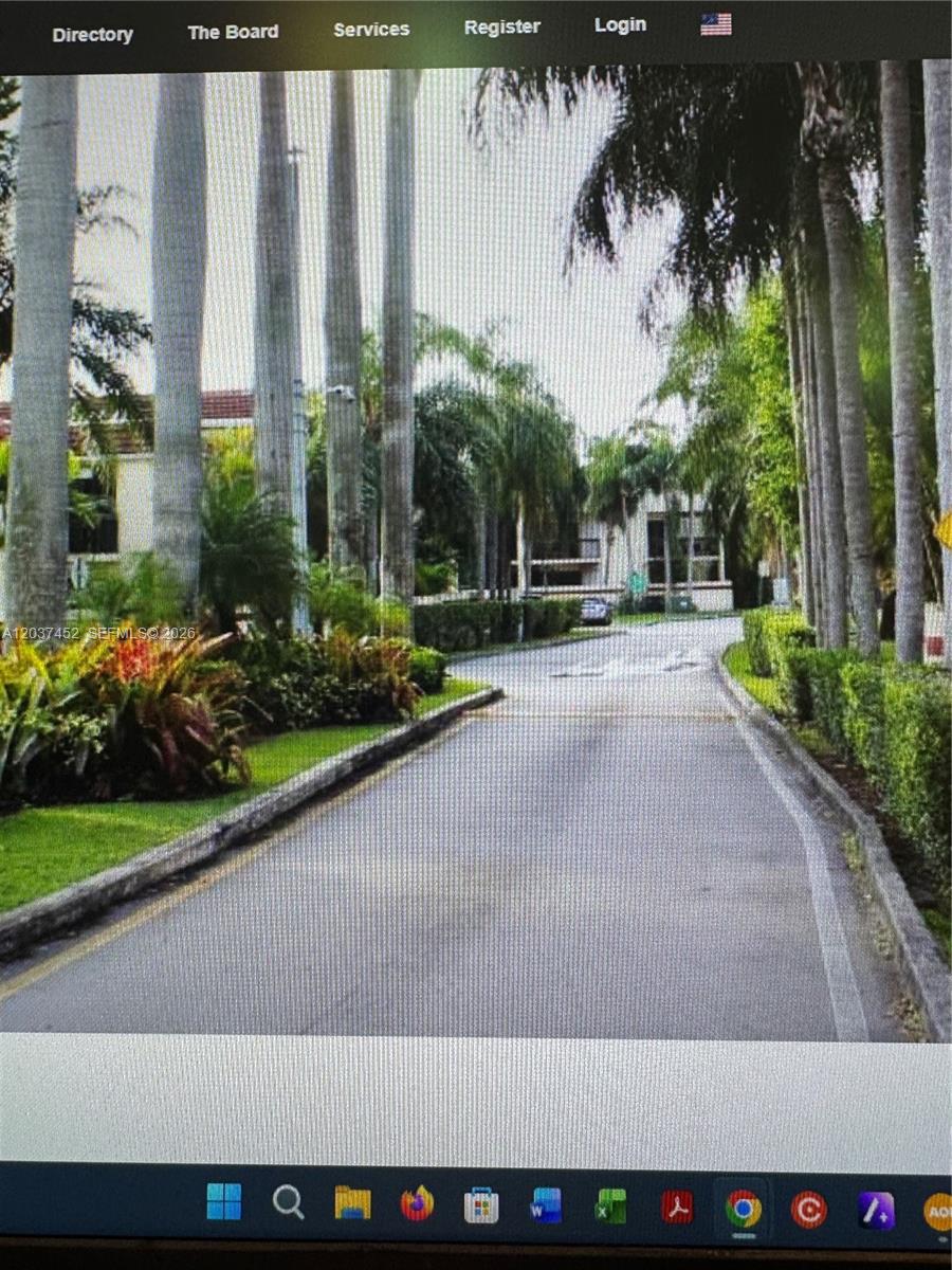 A paved driveway leads toward a residential building surrounded by tall palm trees and landscaping — 12910 SW 88th Ter # 203, Miami FL 33186, MIAMI, FL