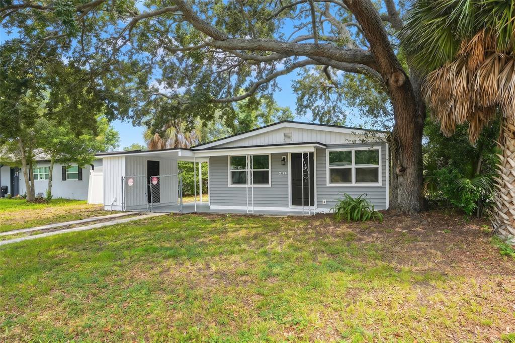 A single-story gray house with a carport and a large tree in the front yard — 4406 W WALLACE AVENUE, TAMPA, FL