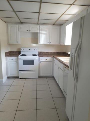 A kitchen features white cabinets, white appliances, and light-colored tile flooring — 720 N Dixie Highway # 202, Lantana FL 33462, LANTANA, FL