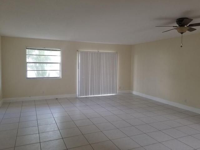 An empty room features light-colored tile flooring, a ceiling fan, and vertical blinds on windows — 720 N Dixie Highway # 202, Lantana FL 33462, LANTANA, FL