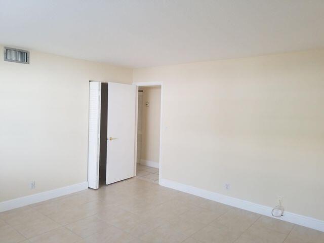 An empty room with beige walls, tile flooring, and an open closet door — 720 N Dixie Highway # 202, Lantana FL 33462, LANTANA, FL