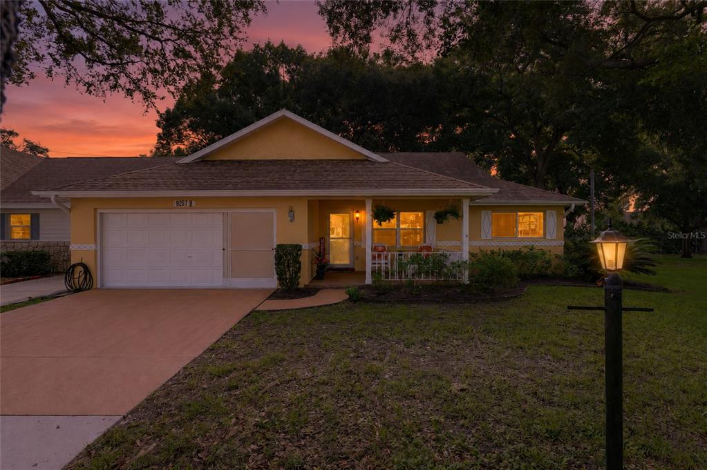 A yellow single-story house features a white garage door and a small front porch — 9257 SW 82ND TERRACE UNIT H, OCALA, FL