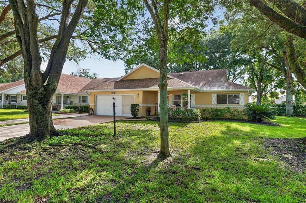 A single-story yellow house with a white garage and a large front lawn with trees — 9257 SW 82ND TERRACE UNIT H, OCALA, FL