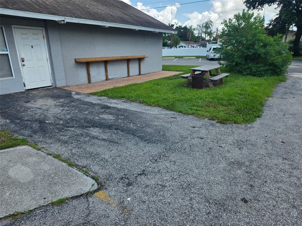 An exterior view of a building with a wooden counter, picnic table, and asphalt parking — 2001 9TH STREET W, BRADENTON, FL