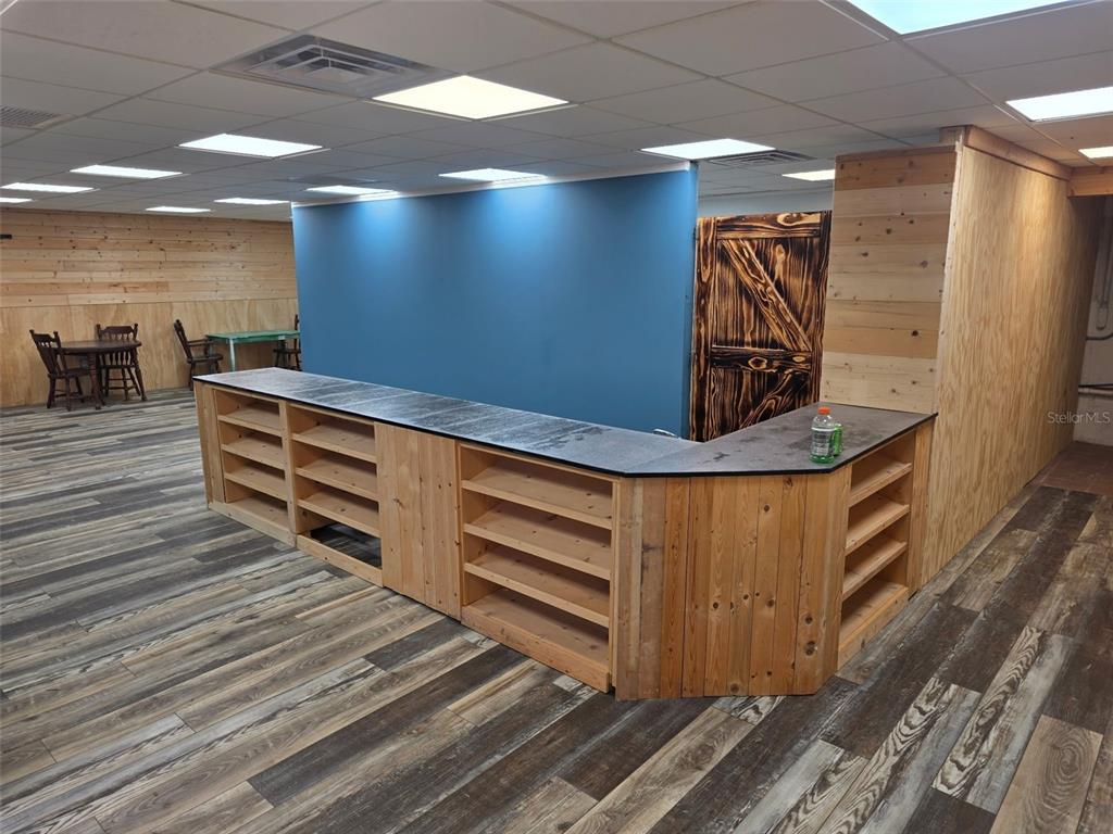 A room with wood-paneled walls, a large L-shaped service counter, and wood-look flooring — 2001 9TH STREET W, BRADENTON, FL