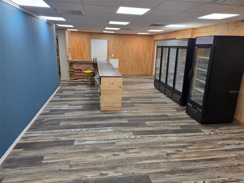 A commercial space features wood-paneled walls, a long service counter, and several glass-door refrigerators — 2001 9TH STREET W, BRADENTON, FL